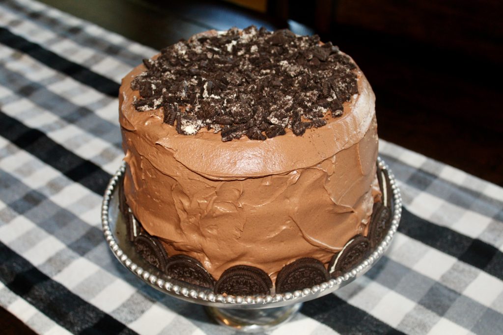 Chocolate cake with Oreos on a silver cake pedestal