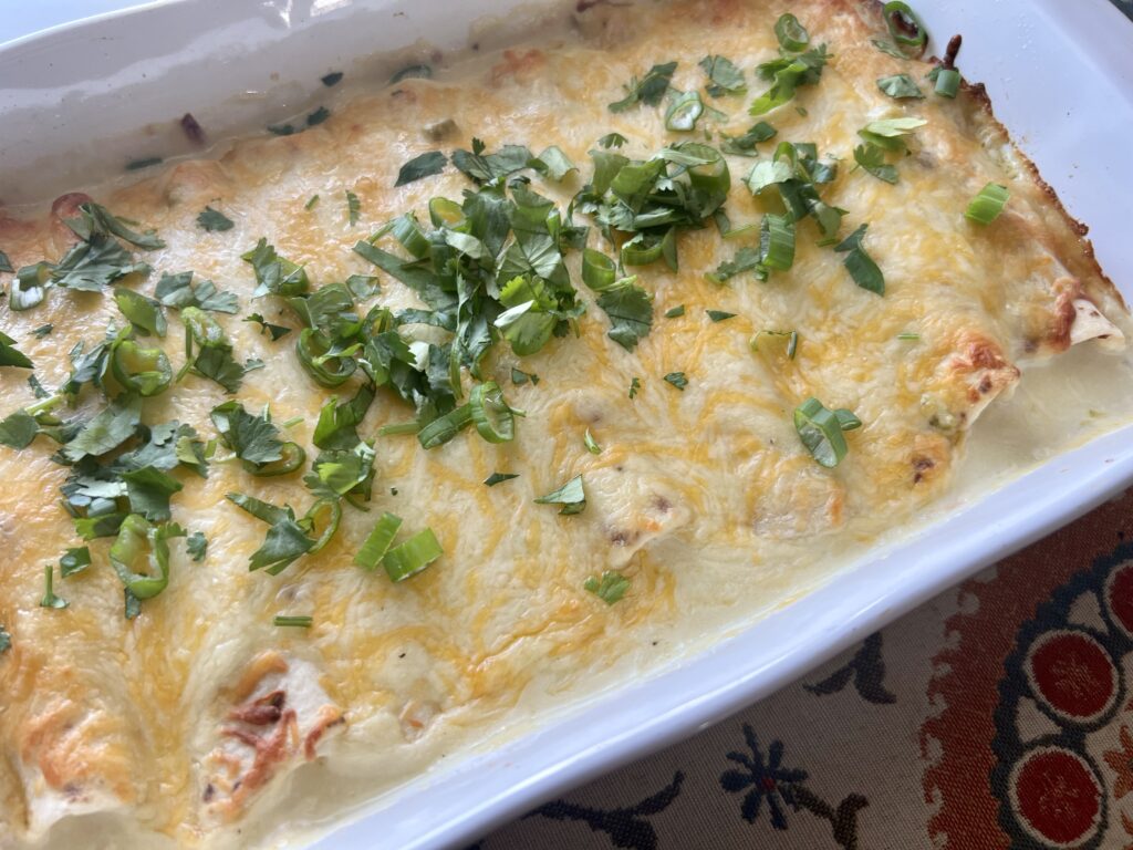 angled pan of creamy chicken enchiladas in a white pan