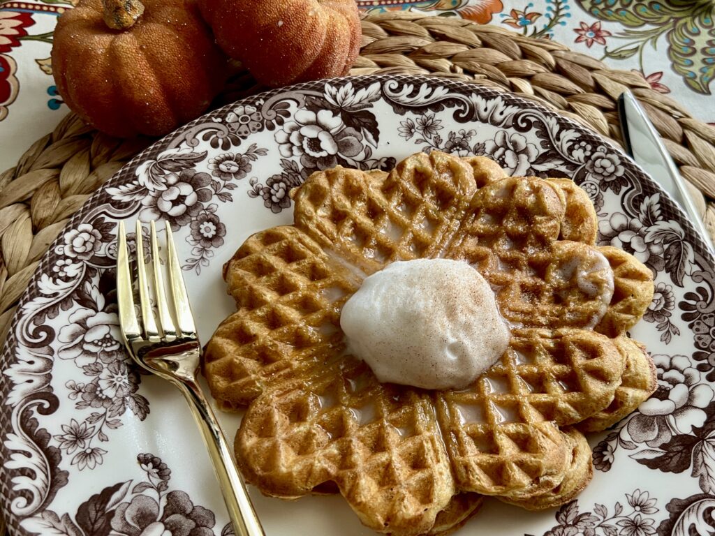 Perfect pumpkin waffle on a plate with a dollop of whipped cream on top