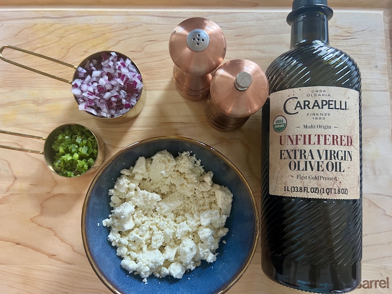 all the ingredients for the crazy feta dip on a wood board