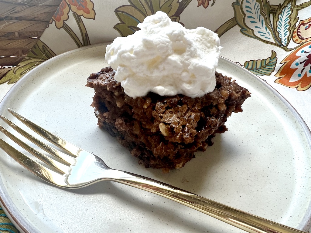 Slice of Picnic Cake with whipped cream on a plate with a gold fork